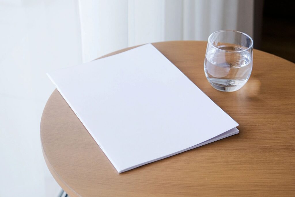 magazine mockup design. blank book mockup on wooden coffee table with glass of water